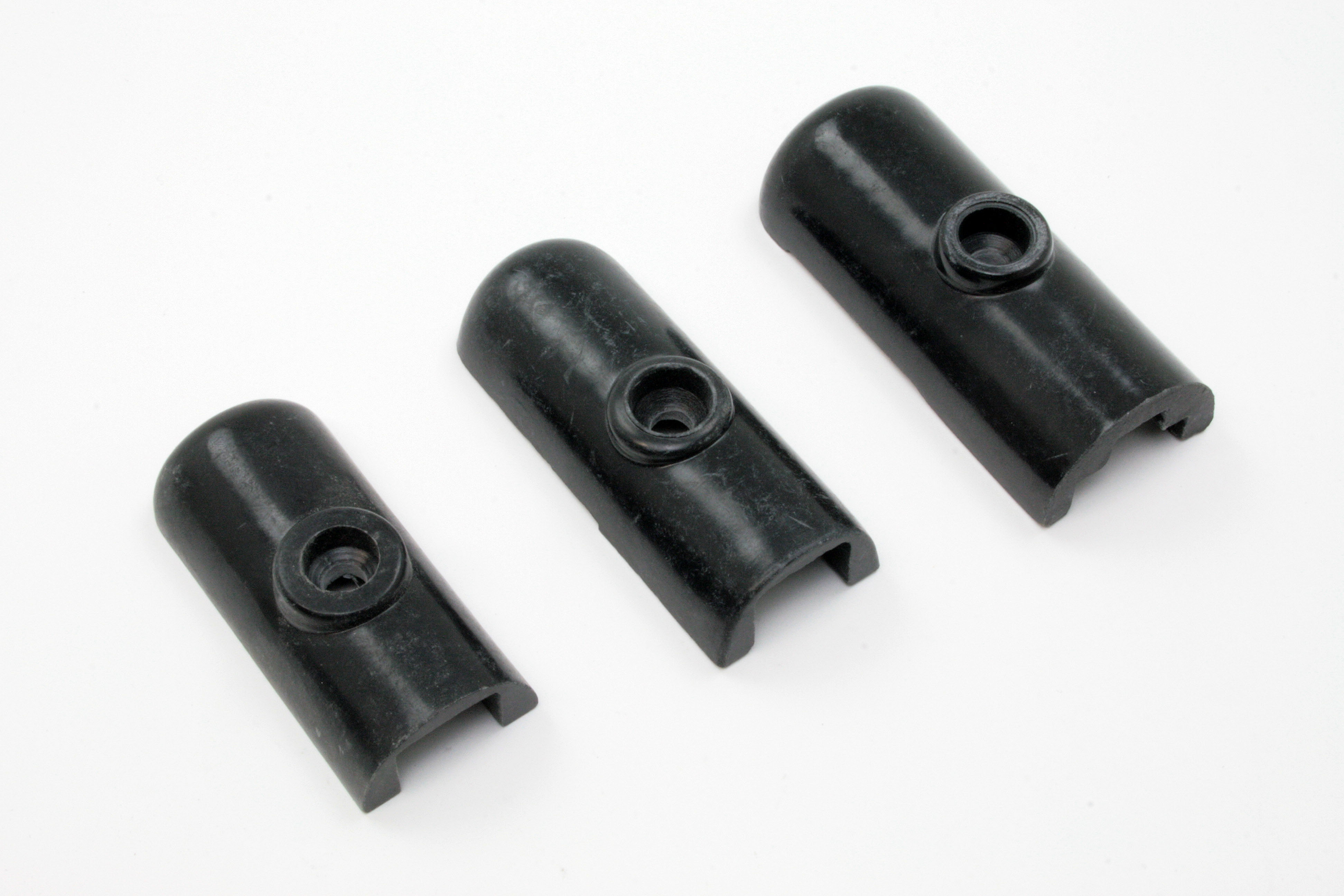 Drei schwarze Kunststoffkappen mit Aussparung und mittiger Bohrung in unterschiedlichen Größen